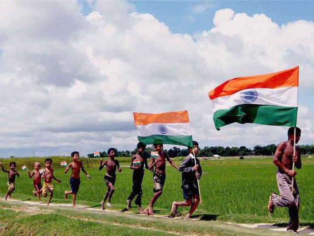 Children holding tricolours, running along a paddy field ahead of Independence day celebrations at Balurghat in South Dinajpur