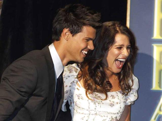 Actress Lea Michele (R) escorts actor Taylor Lautner to the stage at the Hollywood Foreign Press Association's annual installation luncheon in Beverly Hills, California.