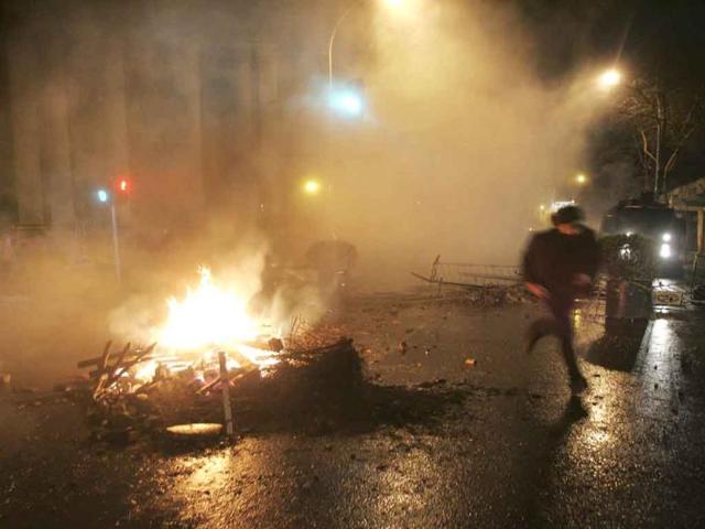 A demonstrator runs past a barricade on fire during a rally in Santiago.
