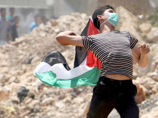 A Palestinian youth throws a stone at Israeli soldiers during clashes following a protest against the nearby settlement of Kadumim, in the village of Kafr Qaddum near the West Bank city of Nablus.