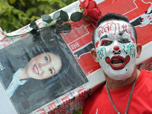 A "Red Shirt" demonstrator with painted face gathers in support of the country's new prime minister, Yingluck Shinawatra (pictured L), after she was endorsed into office at parliament in Bangkok. Yingluck Shinawatra became politically turbulent Thailand's first female prime minister after parliament endorsed her crushing election victory.