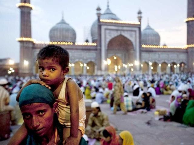 A Muslim woman begs for food handouts and alms as she carries her son while others break the Ramadan fast at the Jama Masjid in New Delhi.