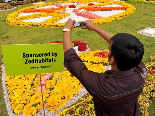 A visitor takes pictures of a floral display at the annual flower show held at the Glass House in Lalbagh Botanical Gardens, Bangalore.