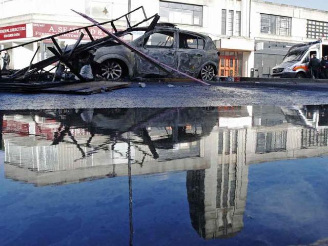 The remains of a burned police car is reflected in water after riots in Tottenham, north London.