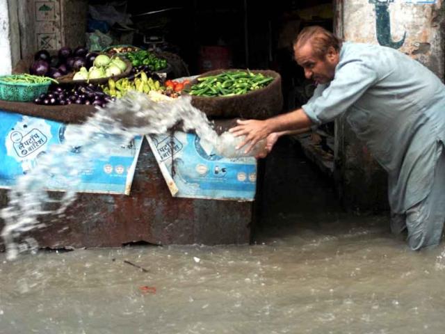 A vegetable vendor throws out rain water from his shop in Amritsar. Heavy rains which fell in several areas of northern India brought respite to the scorching heat which has dominated life in the northern plains in previous days.