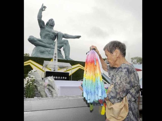 A woman offers thousand paper cranes in front of the Statue of Peace at Nagasaki Peace Park in Nagasaki, southern Japan.