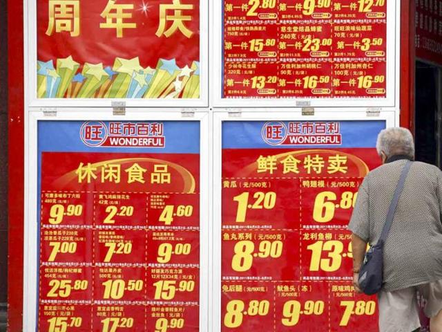 A shopper looks at a board displaying food prices as he walks into a shopping mall in central Beijing.