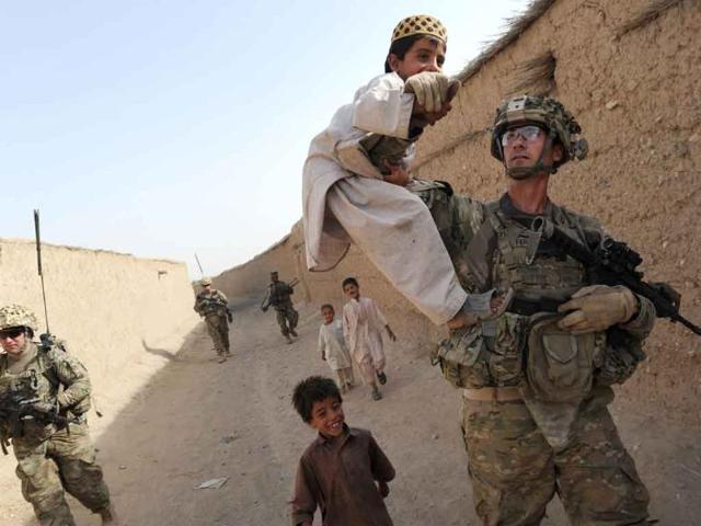 Captain Max Ferguson, company commander of the US troops from the Charlie Company, 2-87 Infantry, 3rd Brigade Combat Team play with Afghan children during a joint patrol with Afghan National Army soldiers at Kandalay village in the southern Afghan province of Kandahar while US troops launched missile attacks on Taliban targets in nearby Kelawai village killing at least three and capturing two insurgents.