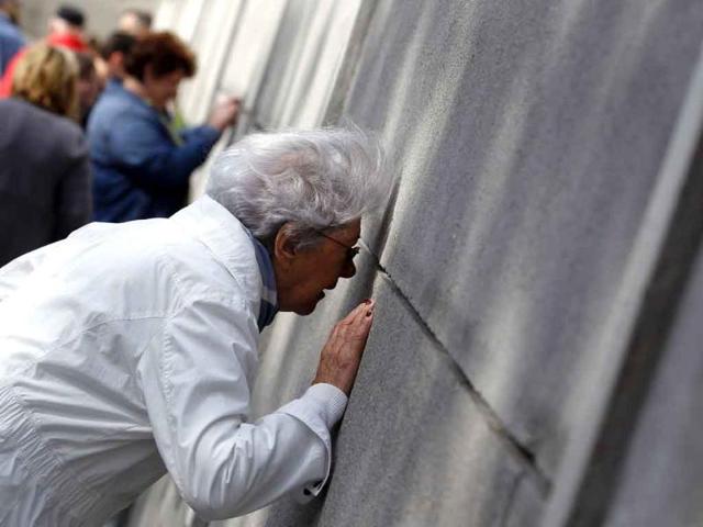 Tourists look through a wall that is part of the former Berlin Wall fortification at the Berlin Wall memorial site in Bernauer Strasse. The German capital is preparing to mark the 50th anniversary of the building of the Berlin Wall, which was erected on August 13, 1961.
