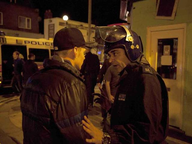 A police officer searches a man as members of the community march to reclaim their streets in Enfield, North London.