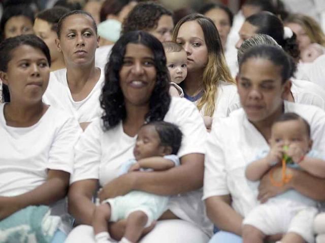 Inmates hold their babies as they watch fellow prisoners take part in the third annual Miss Penitentiary beauty pageant at the Women's Prison of Brasilia.