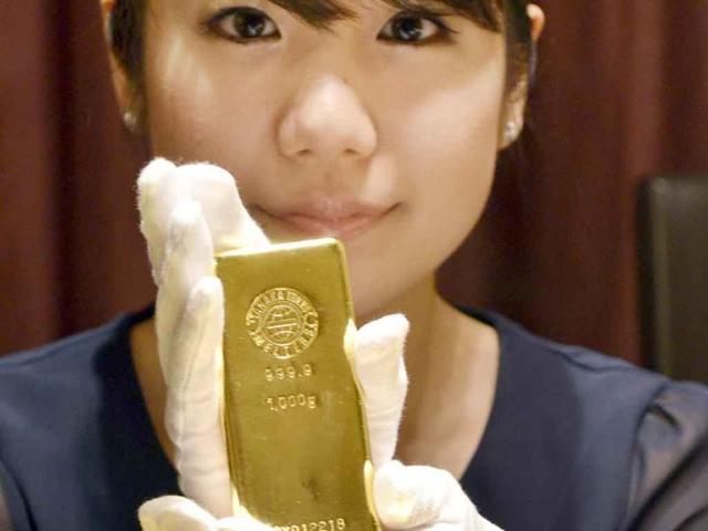 An employee of Japanese jeweller Tanaka Kikinzoku poses with 1-kilogram gold bars at the company's main shop in Tokyo. Gold prices surged past $1,800 an ounce as investors bought up the safe haven as markets around the world slump due to ongoing fears about the global economy.