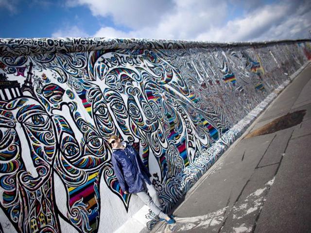 A tourist leans against a painted part of the former Berlin Wall named East Side Gallerie.