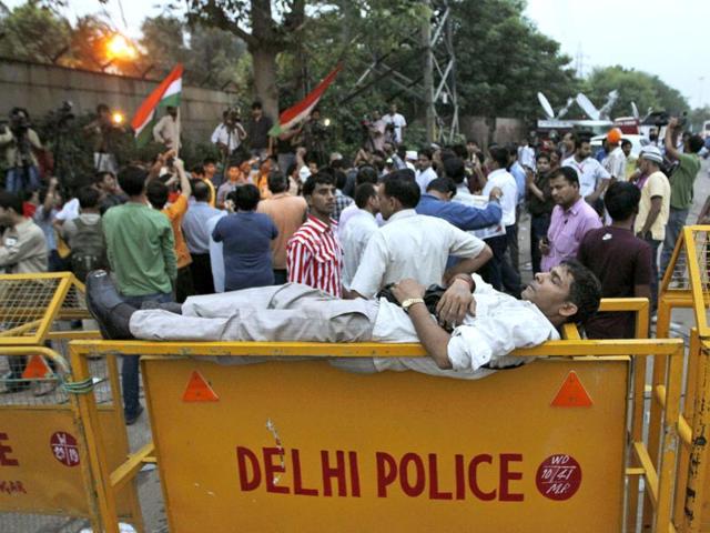A man sleeps on a police barricade as others shout slogans while waiting outside a gate of Tihar jail in New Delhi.