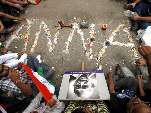 Supporters of anti-corruption activist Anna Hazare place a portrait of Mahatma Gandhi (bottom) near a marking on the road that reads 'Anna' outside Tihar jail in New Delhi.