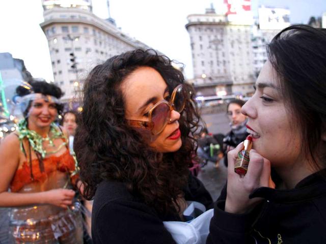 A woman applies lipstick on another as they take part in a SlutWalk rally against sexual abuse and inequality in Buenos Aires.