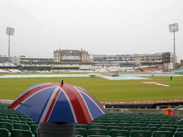 A spectator waits under an umbrella as rain delays play after the lunch interval during day 3 of the fourth Test match between England and India at The Oval Cricket Ground in London.