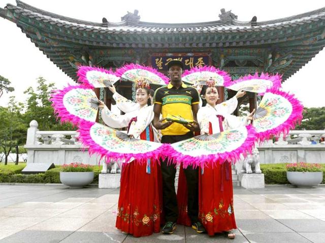 World record holder Usain Bolt of Jamaica poses with his new running spikes and promoters wearing traditional Hanbok in Daegu, southeast of Seoul.