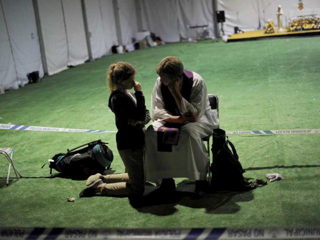 A young woman confesses to a priest in the open air at the base of Cuatro Vientos, Madrid on Saturday.
