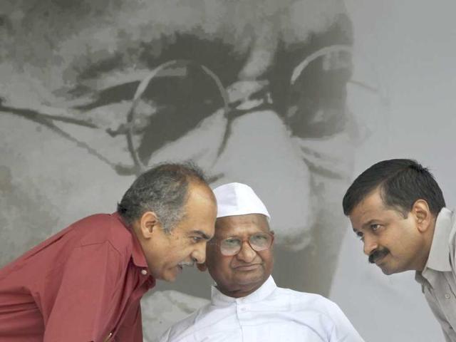 Social-activist-Anna-Hazare-center-listens-as-associates-Prashant-Bhushan-left-and-Arvind-Kejriwal-right-discuss-as-they-sit-on-the-stage-with-a-backdrop-of-a-giant-portrait-of-Mahatma-Gandhi-during-Hazare-s-hunger-strike-in-New-Delhi