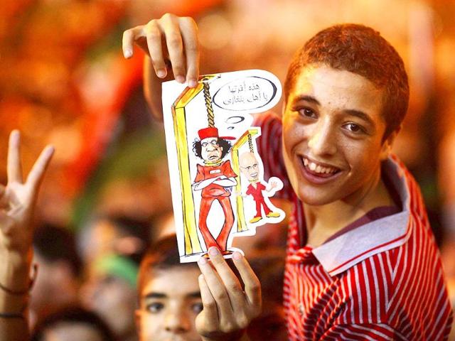 A boy holds a drawing depicting Muammar Gaddafi and his son Seif al-Islam being hanged during celebrations of the capture in Tripoli of the son at the rebel-held town of Benghazi, Libya.