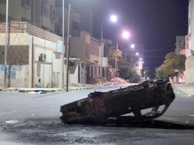A wrecked car blocks a deserted street in Tripoli.