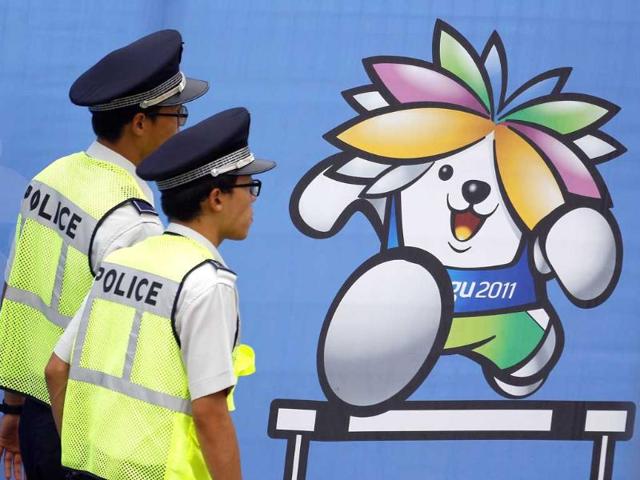 Police patrol past a fence with an image of Sarbi, the official mascot for the IAAF Daegu 2011 World Championship, in front of the athletes village in Daegu.
