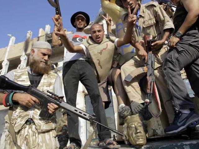Rebel fighters stomp on the head of a Muammar Gaddafi statue inside his compound in Bab al-Aziziya in Tripoli, Libya.