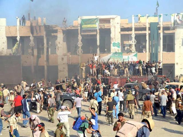 Rebels and their supporters celebrate outside Libyan leader Moamer Kadhafi's heavily damaged Bab al-Azizya compound in the centre of Tripoli as explosions and gunfire rocked the streets of the Libyan capital.