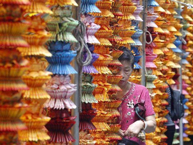 A person walks between strings of lotus-shaped incense papers during a mass prayer for the Chinese Hungry Ghost Festival in Taipei.