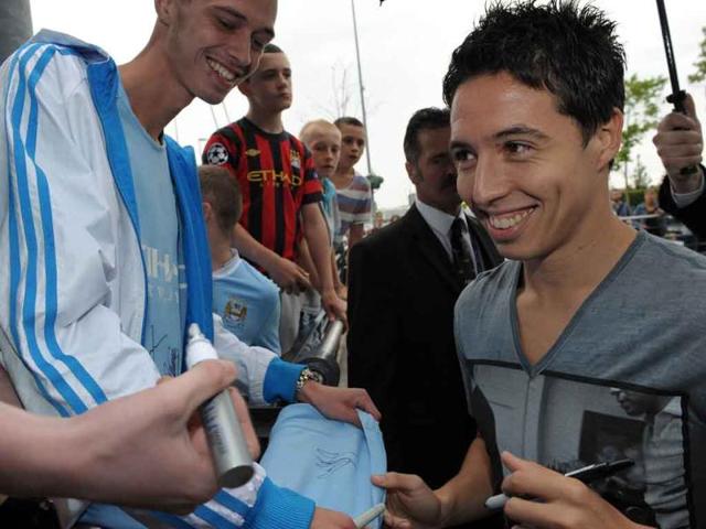 French footballer Samir Nasri signs autographs as he is greeted by fans outside Manchester City's Etihad Stadium in Manchester, north-west England.