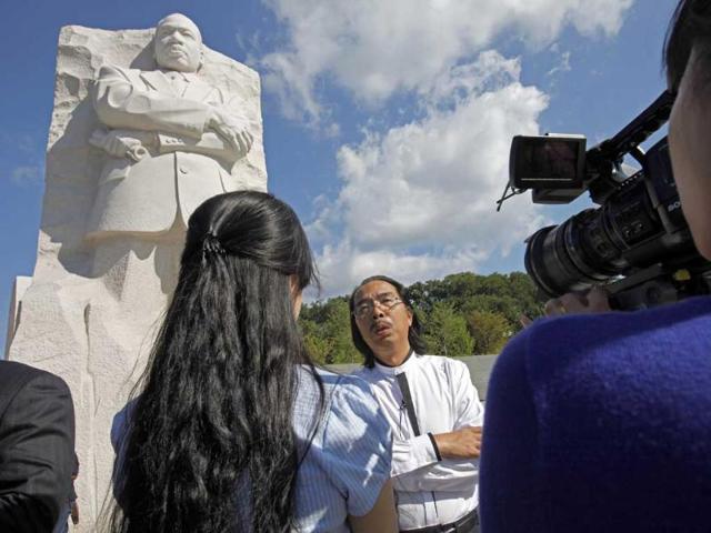 Sculptor Lei Yixin, of China, is interviewed by a Chinese television crew in front of his sculpture of Dr. Martin Luther King, Jr.