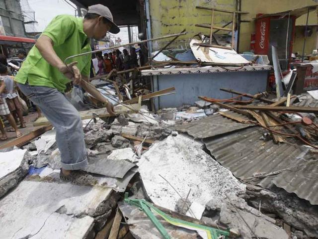 A man salvages steel rods on the rubble of a collapsed wall as it was knocked down by strong winds, in suburban Novaliches, Quezon City, Philippines.