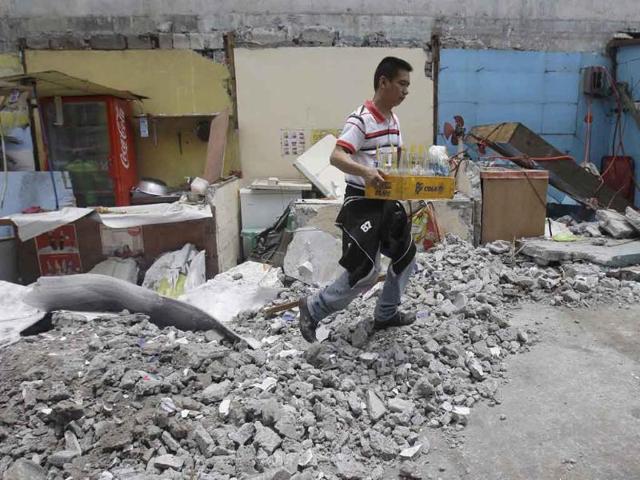 A man salvages bottles along the rubble of a collapsed wall as it was knocked down by strong winds, in suburban Novaliches, Quezon City, Philippines.