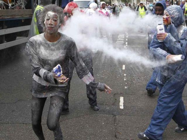 A reveller throws powder at others during a J'ouvert celebration at Ladbroke Grove in London which marks the start of the Notting Hill Carnival.