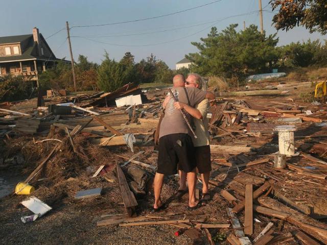 Billy Stinson (R) is comforted by his friend David Alan Harvey as he looks over the remains of his cottage in Nags Head, North Carolina.
