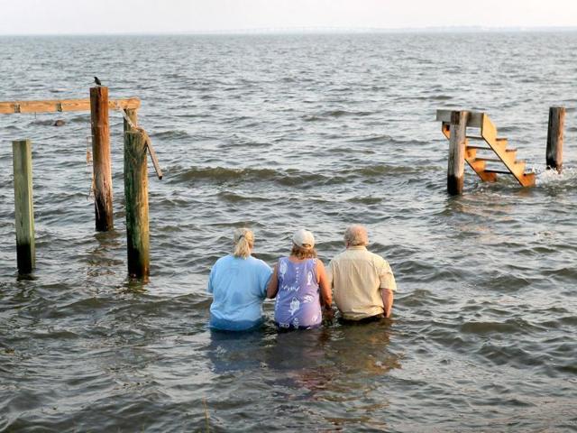 Billy Stinson (R), his wife Sandra Stinson (C) and daughter Erin Stinson walk out to watch the sunset from the steps where their cottage once stood in Nags Head, North Carolina.