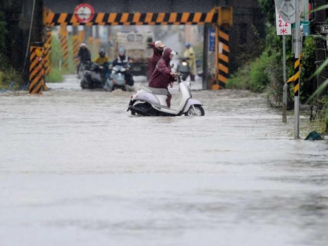 Local motorcyclists push their motorbikes through floodwaters caused by Typhoon Nanmadol in Linbian, Taiwan's southern Pingtung county.
