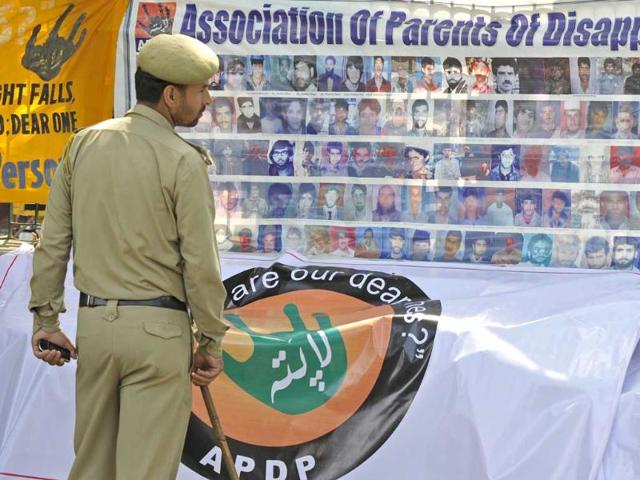 A policeman looks at portraits of missing people during a protest rally to demand information of their whereabouts during the International Day of the Disappeared in Srinagar.