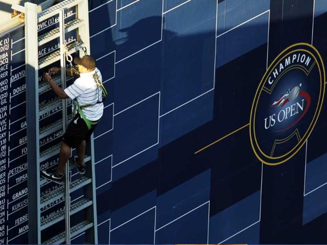 A man changes the bracket displayed during the first round of the US Open tennis tournament in New York.