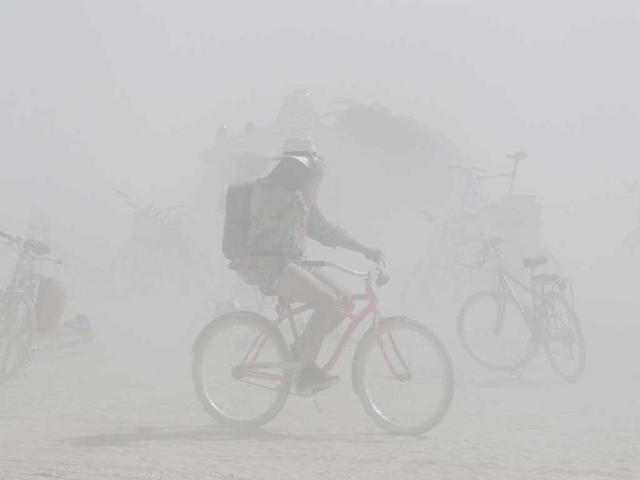 A participant rides a bicycle across the Black Rock desert during a dust storm in the midst of the the Burning Man Rites of Passage arts and music festival in Nevada.