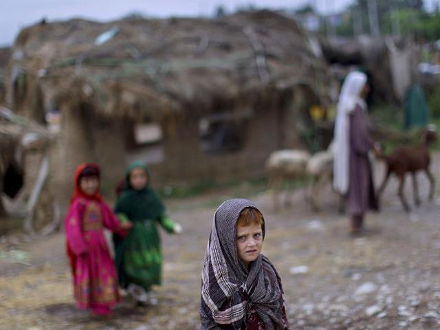 Afghan refugee girl Naseebah Zarghoul, bottom, looks on while she and other children celebrate the second day of Eid al-Fitr festival which marks the end of the Muslim fasting month of Ramadan, in a slum on the outskirts of Islamabad, Pakistan.