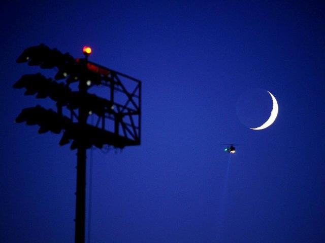 A helicopter flies past the crescent moon over the soccer fields of Home Depot Center where the US Men's National Team practiced in Carson, California.