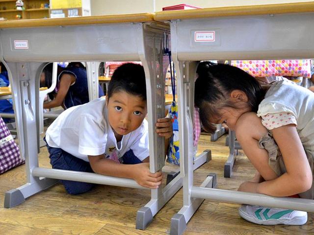 Elementary school children take cover under their desks as part of a nationwide earthquake drill at a Tokyo elementary school.