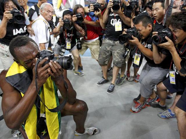 Usain Bolt of Jamaica uses a camera after winning the men's 200 metres final at the IAAF World Athletics Championships in Daegu.