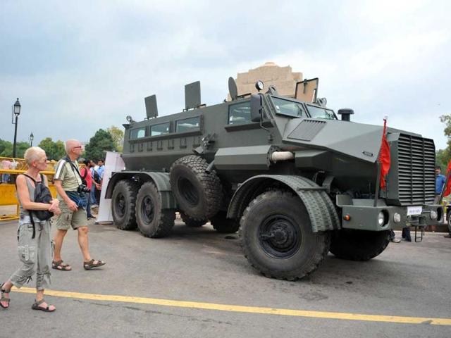 Tourists walk past a display of the first locally produced mine protected armoured troop carrier, produced by Defence Land Systems India (DLSI), in front of the India Gate monument in New-Delhi.
