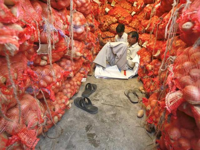Men sit amid stacked sacks of potatoes at a vegetable wholesale market in Noida, on the outskirts of New Delhi.