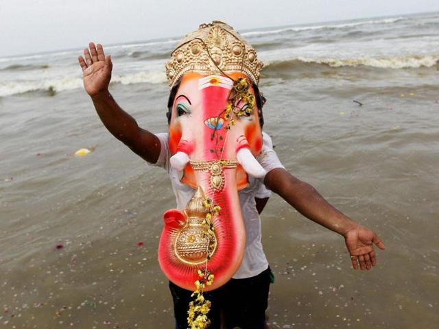 A devotee carries an idol of Lord Ganesha for immersion in Marina beach during Ganesh Utsav in Chennai.