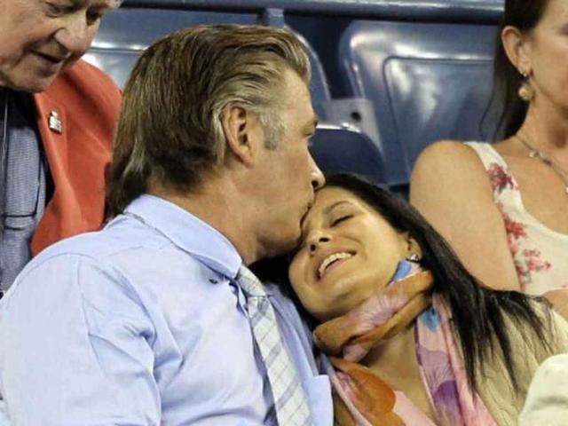 Alec Baldwin (L) cozies upto girlfriend Hilaria Thomas while watching the match between Roger Federer of Switzerland and Santiago Giraldo of Colombia during US Open 2011.