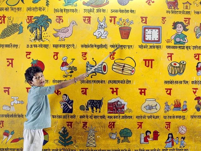 In this photo taken on Wednesday, a young Indian boy reads a picture on a wall at a government run school on International Literacy Day in Allahabad, India.